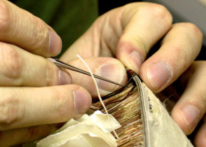 A conservator sews the binding of a book