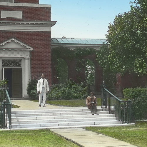 Old photo of two people in front of a building on campus
