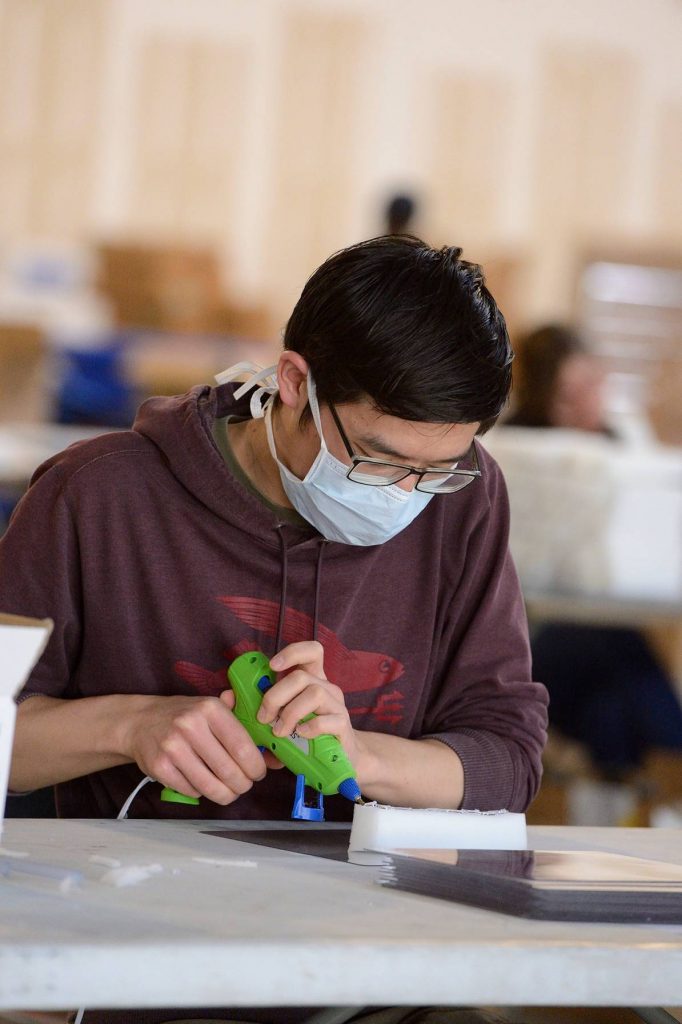 masked student using a hot glue gun