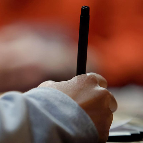 detail of hand holding a pen and writing