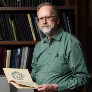 archivist Jim Stimpert holding a book