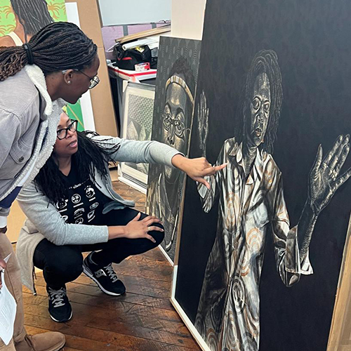 Two women looking at a large painting on canvas