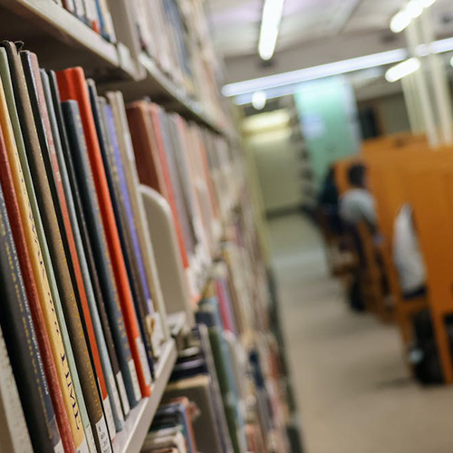 detail view of library stacks with books and students in study carrels